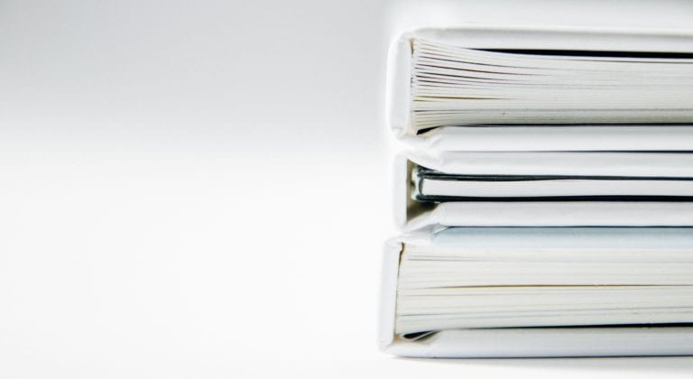 Stack of papers and binders against white background